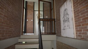 Una escalera con barandilla de metal, paredes de ladrillo y un dibujo enmarcado en la pared.
