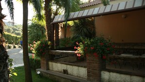 A patio area with a brick wall, a wooden bench, and red flowers. - Villa Rosi - Monolcale with pool (laureana cilento)