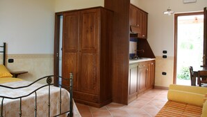 A bedroom with a bed, wooden wardrobe, and a small table. - Villa Rosi - Monolcale with pool (laureana cilento)