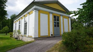 A building with a symmetrical facade, large windows, and a gravel pathway leading to the entrance.