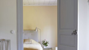 A room with a wooden floor, a bed with a headboard, a nightstand, a lamp, and a chair.