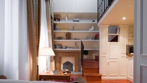 A cozy living room with a fireplace, a staircase, and a bookshelf.
