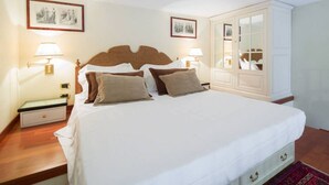 A neatly made bed with a wooden headboard, two bedside lamps, a nightstand, and a wardrobe with a mirror.
