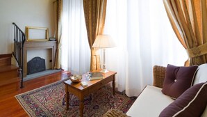 A room with a fireplace, a wooden table with a lamp, a sofa, and a patterned rug.
