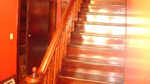 Un escalier en bois, muni d’une rampe, menant à une porte fermée.