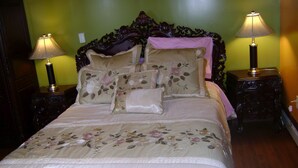 Un lit avec une literie à motifs floraux, deux tables de chevet avec des lampes et un mur vert.