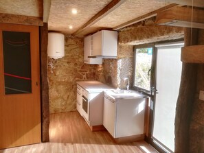 A compact kitchen with a stone wall, wooden ceiling, and a window. - Casa da Eira - Fair between the Sea and the Serra / Camino de Santiago (Marinhas)