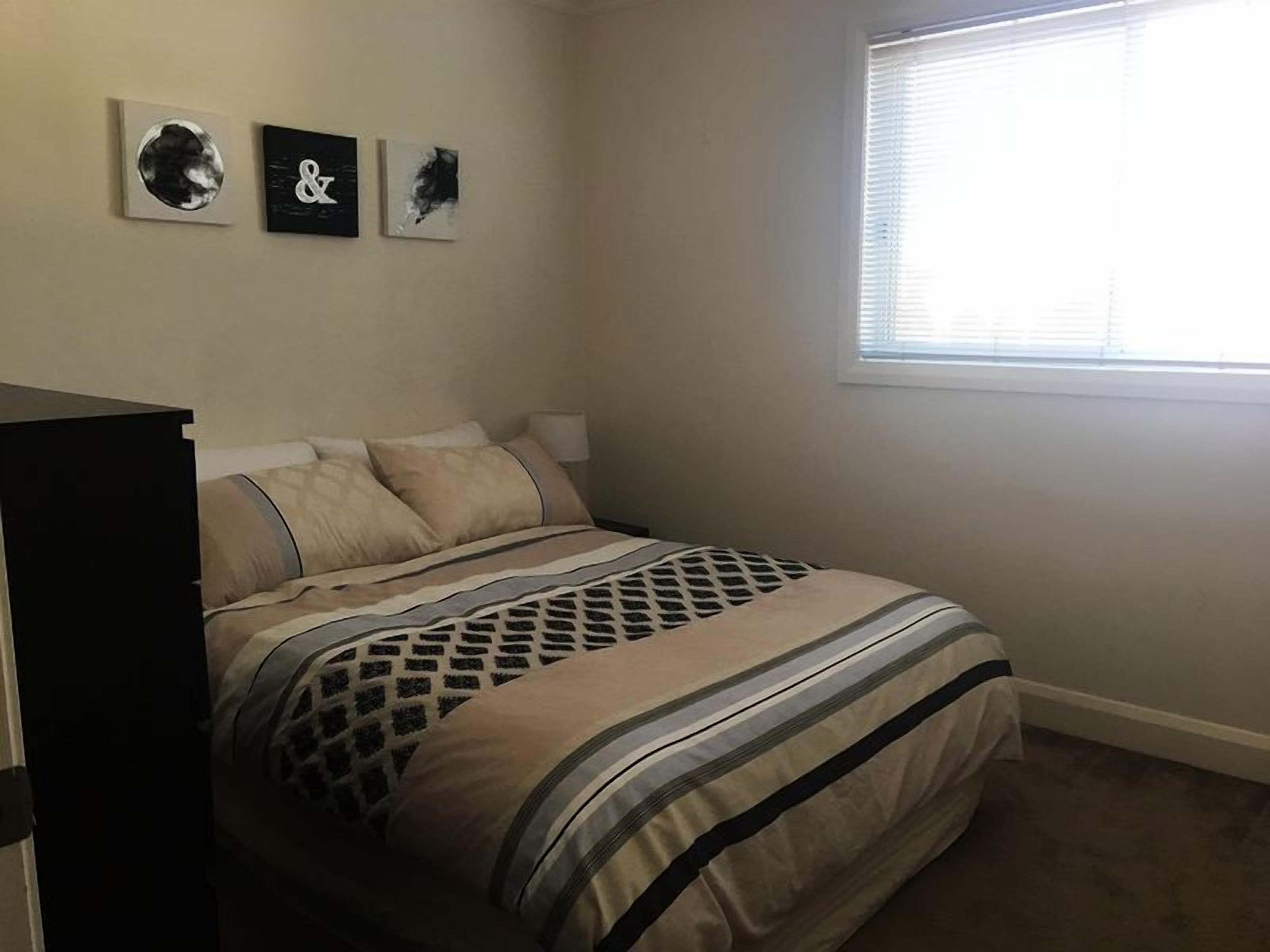 Ein Schlafzimmer mit einem Bett, einem Schminktisch und drei an der Wand befestigten Kunstwerken.