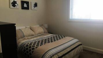 Ein Schlafzimmer mit einem Bett, einem Schminktisch und drei an der Wand befestigten Kunstwerken.