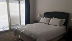 Ein Hotelzimmer mit einem großen Bett, einem Nachttisch, einer Lampe und einer Schiebetür.
