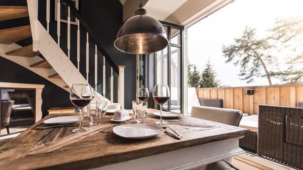 A dining area with a wooden table set for two, two wine glasses, and a candle. - 5 star luxury apartment m. daily cleaning, fireplace u. great water view (Loddin)
