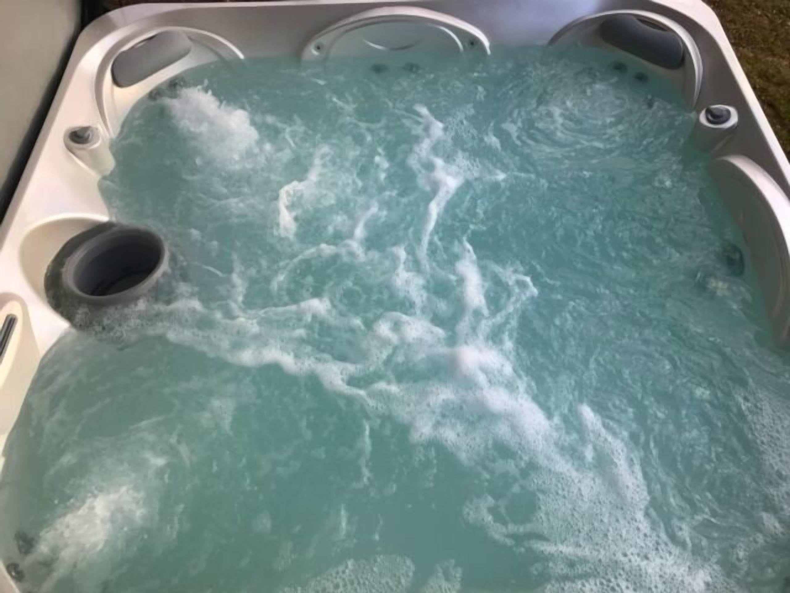 Een jacuzzi met helder water en zichtbare bubbels, wat aangeeft dat deze in gebruik is.