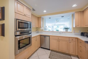 Una cocina moderna con electrodomésticos de acero inoxidable, armarios de madera y un amplio ventanal que proporciona luz natural.