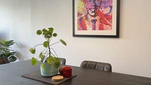 Una sala de conferencias con una larga mesa, sillas, un cuadro abstracto enmarco, una planta en maceta y una taza roja.