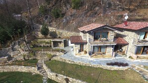A stone house with a balcony, surrounded by a stone retaining wall and a stone staircase.