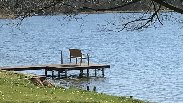 A wooden dock extending into a lake with a single chair on it. - House Seewind Hohenfelden (Hohenfelden)