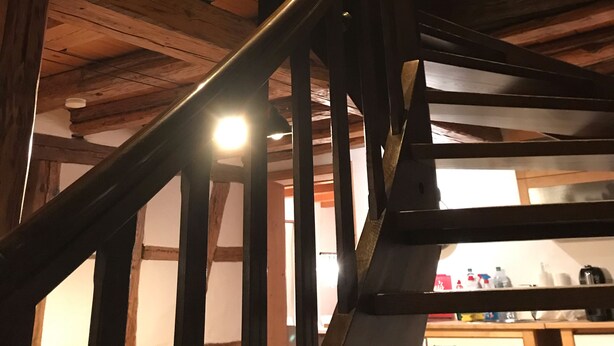 Un escalier en bois avec une rampe métallique menant à un niveau supérieur.