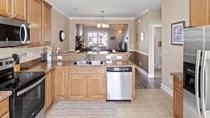 A spacious kitchen with wooden cabinets, a stainless steel refrigerator, and a dishwasher. - Egret Run #214 Beautiful Condo (North Myrtle Beach)