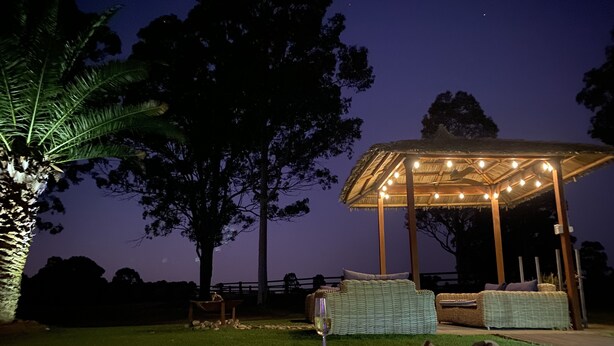 Tuberculo caliente con una pérgola y mobiliario de mimbre en un jardín por la noche.