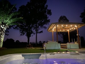 Tuberculo caliente con una pérgola y mobiliario de mimbre en un jardín por la noche.