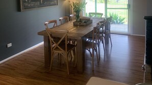 A dining area with a wooden table and chairs, a world map on the wall, pendant lights, and a view through a glass door. - Bella Farm Hunter Valley. Rustic & Elegant Farmhouse with Outdoor Spa. Firepit. (Pokolbin)
