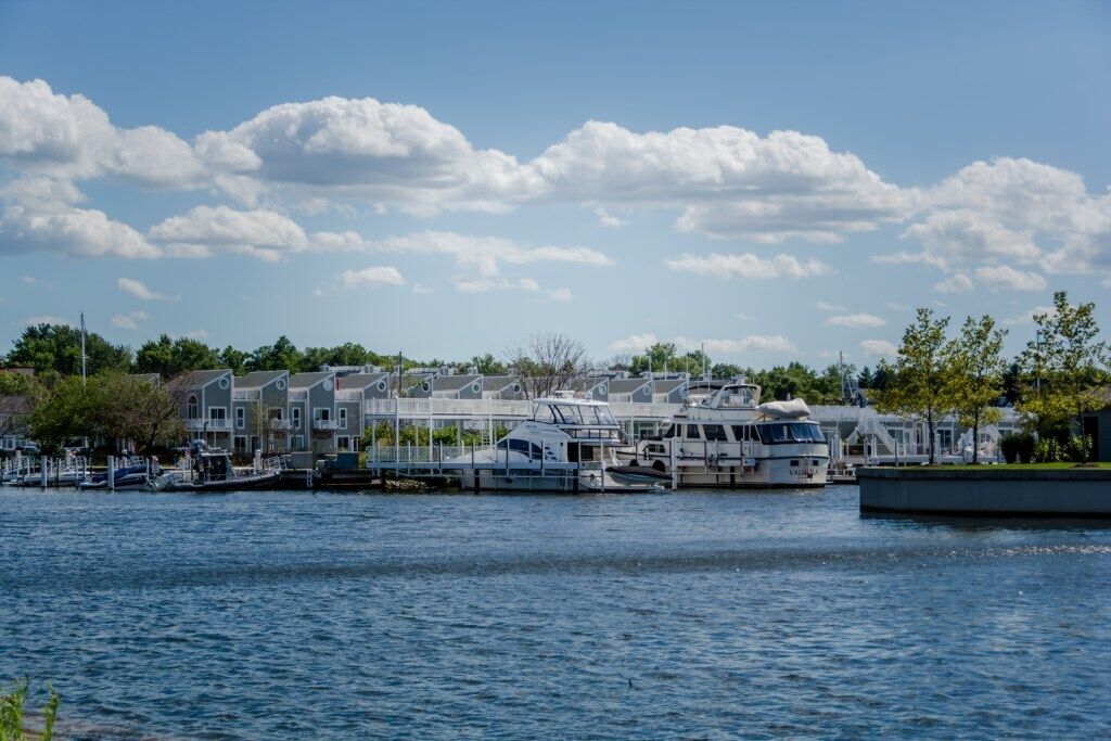 A marina with several boats docked, a waterfront building, and a clear sky.