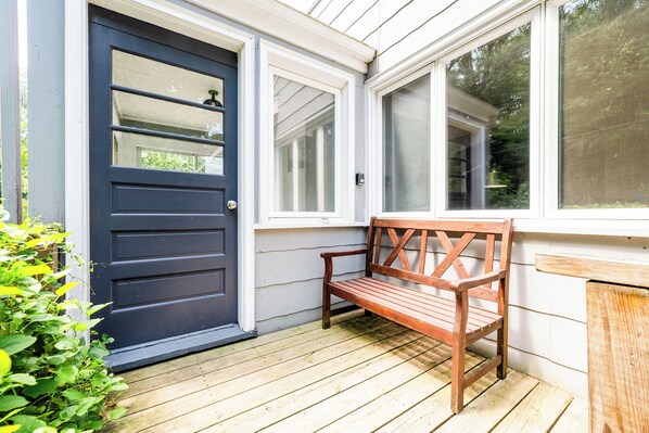 A wooden bench outside a house with a dark blue door and white siding. - (2027 OPEN!) Union Pier Beach Style Cottage Close to Lake Michigan! (Union Pier)