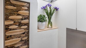 Een modern interieur met een stenen muur, een potplant en een vaas met bloemen.