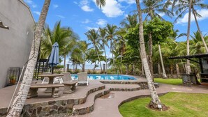 A pool area with stone steps, palm trees, and a clear blue sky.
