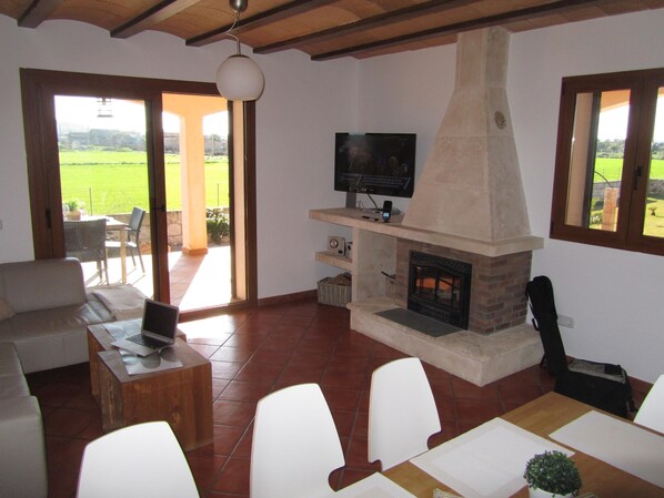 Una sala de estar con chimenea, televisor y una computadora portátil sobre una mesa de centro de madera.