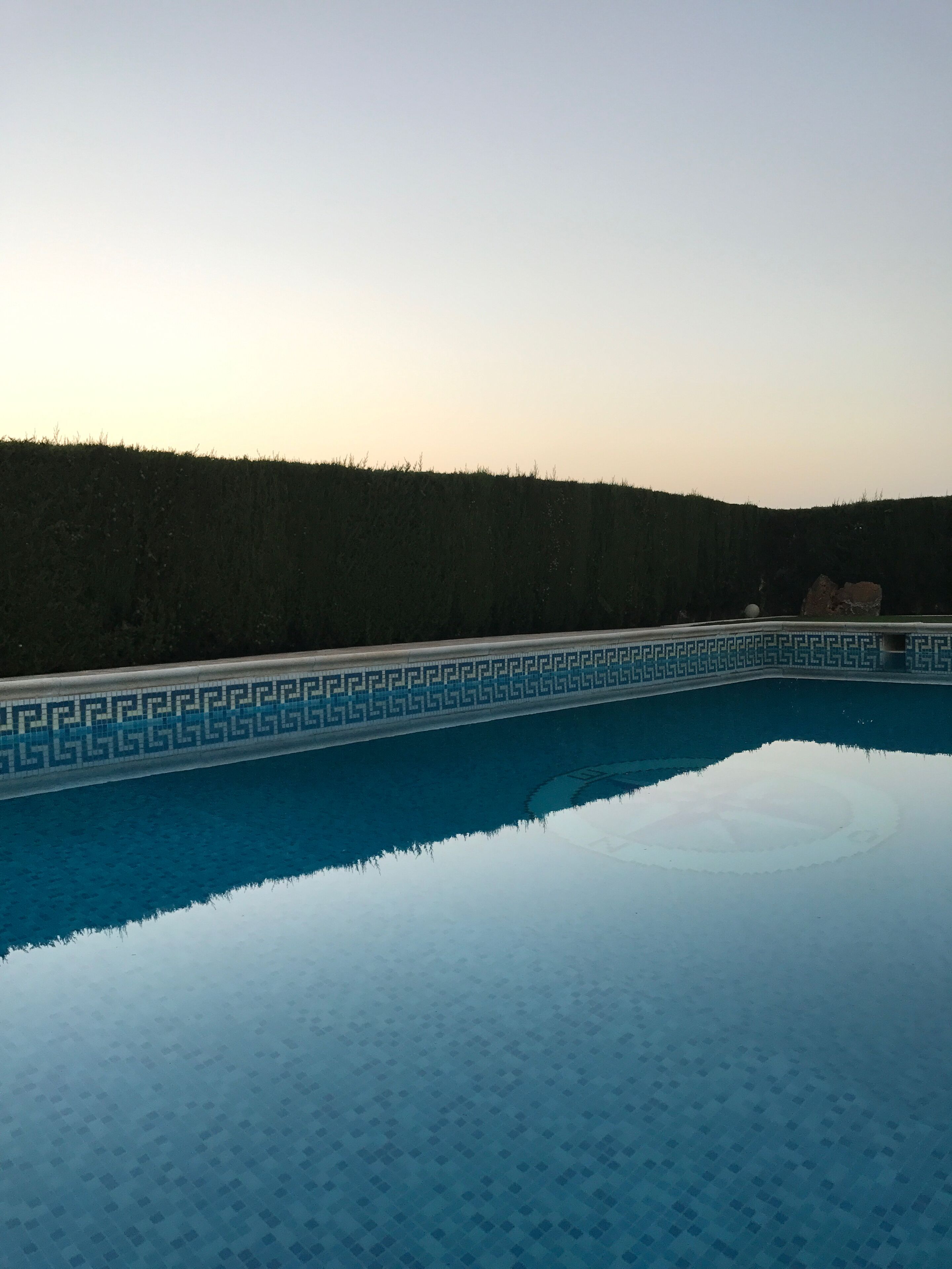 Piscina com padrão geométrico de azulejos e reflexo nítido.