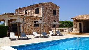 A building with a stone facade, a swimming pool, and lounge chairs. - Wonderful finca with a large pool and barbecue kitchen near Es Trenc!  (Campos)