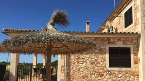 A stone building with a thatched umbrella, a gate, and a staircase leading to a door. - Wonderful finca with a large pool and barbecue kitchen near Es Trenc!  (Campos)