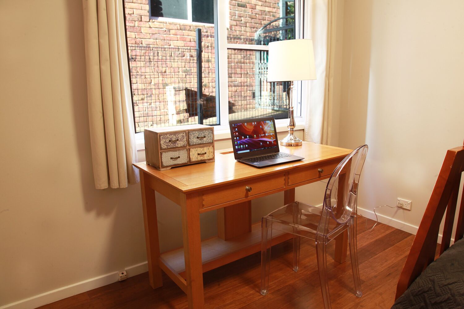 A wooden desk with a laptop, a lamp, and a decorative box.