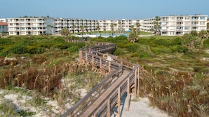 A wooden boardwalk leading to a beachfront hotel with multiple balconies and a pool area. - CRC 1302 - Beautiful Oceanfront Condo with Amazing Views (St Augustine)