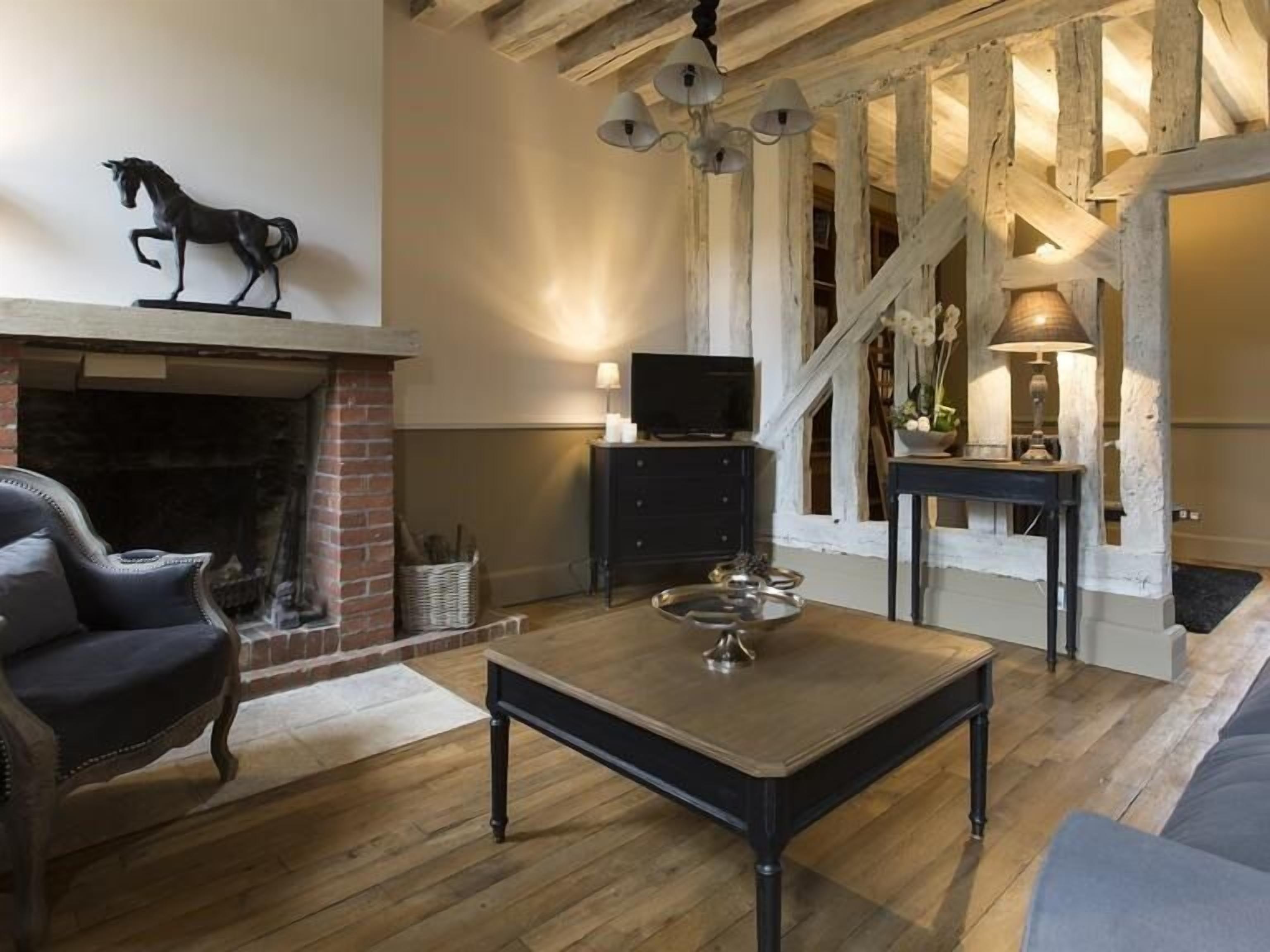 Een gezellige woonkamer met een open haard, een televisie en een trap naar een hoger niveau.