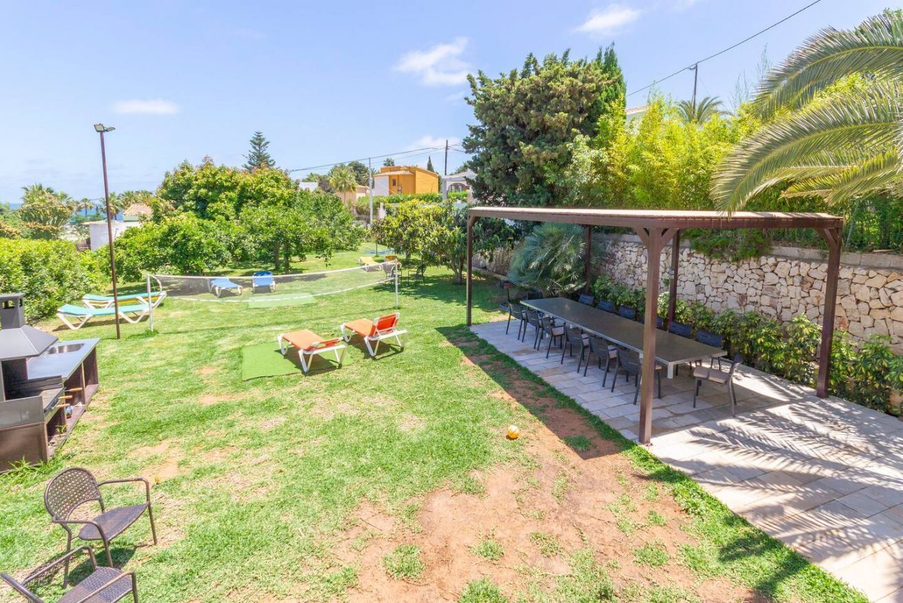 Ein Garten mit Grillplatz, Sitzgelegenheit im Freien und einer Pergola.