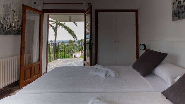 Ein Schlafzimmer mit einem großen Bett, zwei Kissen und Blick ins Freie.