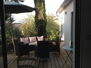 Une terrasse extérieure aménagée avec des meubles en osier, une table ronde et un grand parasol.
