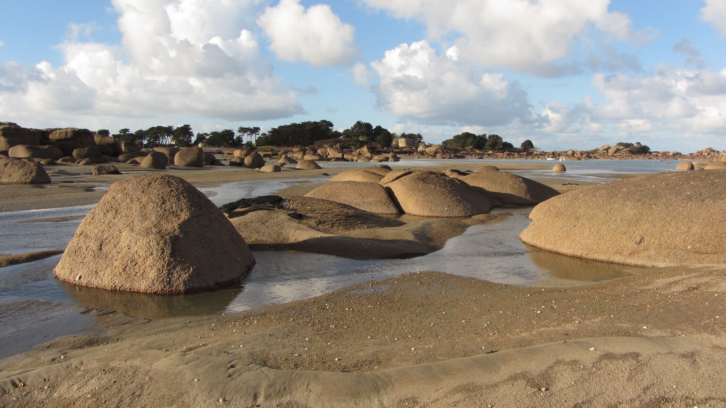 Een strand met grote zandvormingen en een heldere lucht.
