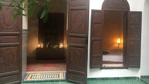 An open wooden door leading to a room with a patterned floor and a small window with a lamp.