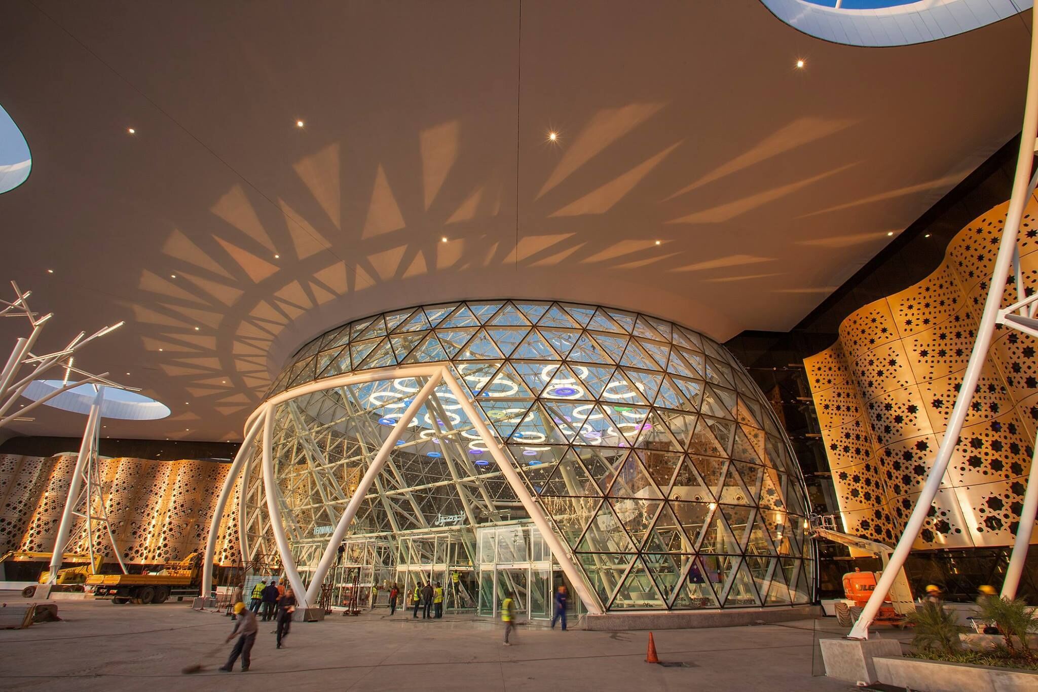 Une structure architecturale moderne dotée d’un grand dôme de verre et de motifs géométriques sur les murs.