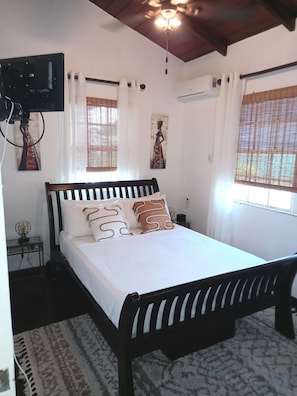Relax in this serene bedroom with a large bed, ceiling fan, and window with blinds.