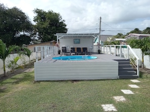 Relax by the pool surrounded by lush greenery and a deck.