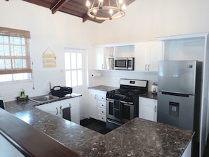 Enjoy cooking in this well-equipped kitchen with a central island, stainless steel stove, oven, and ample cabinetry storage.
