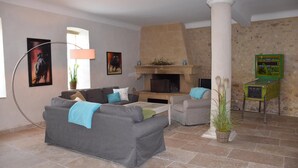 A living room with a grey sofa, a coffee table, and a fireplace. There are two framed pictures on the wall, a lamp, and a plant.