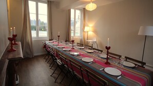 Ein Essbereich mit einem langen Tisch, gedeckt für eine Mahlzeit, mit Kerzen und einer Lampe.