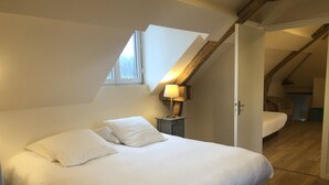 Ein Schlafzimmer mit einem großen Bett, einem Nachttisch, einer Lampe und einem Fenster.