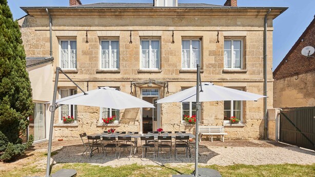 Ein Steinhaus mit einer Terrasse, die Tische und Sonnenschirme bietet.