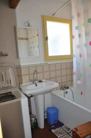 Ein kleines Badezimmer mit Waschbecken, Spiegel und Fenster.